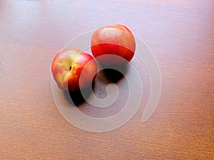 Two nectarines on a wood surface