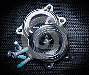 Two new hub bearings with spare mounting bolts, for a sports car. Black background, metal mesh