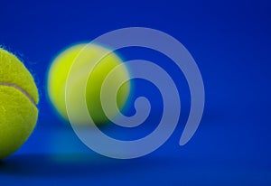 Two new tennis balls on blue court with light from left