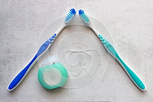 Two new toothbrushes  and container of dental floss. Dental floss laid out in the shape of a tooth. Tools for personal oral hygien photo