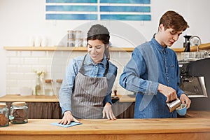 Two nice baristas working at bar counter, looking happy.