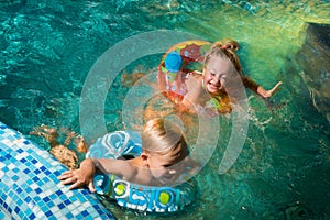 Two nice children swiming in blue pool