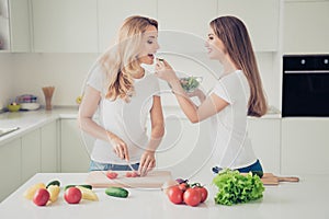 Two nice cute lovely attractive charming cheerful people blonde mom mum cooking tasting good food in modern light white