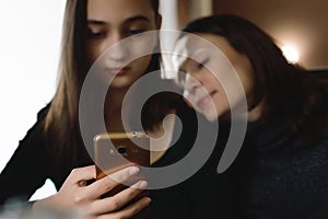 Two nice girls are sitting in a cafe and using mobile phones