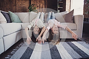 Two nice lovely attractive charming different cheerful cheery friendly girls lying on divan upside-down having fun day