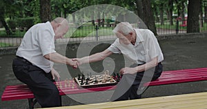 Two nice seniors men playing the chess game, using clock and having a talk