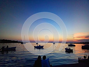 Two at Noval sunset in a quiet harbor with boats