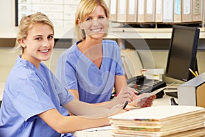 Two Nurses Working At Nurses Station