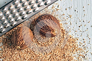 Two nutmeg and a metal grater against ground powder on a wooden table. View from above with space copied photo