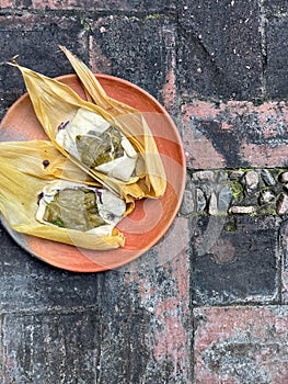 Two Oaxacan tamales with hoja santa wrapped on the outside of the masa photo