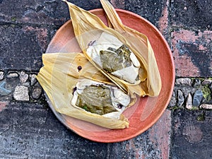 Two Oaxacan tamales with hoja santa wrapped on the outside of the masa photo