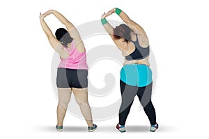 Two obese woman stretching hands on studio