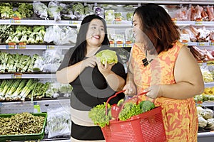 Two obese women buying organic vegetables