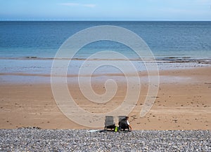 Two occupied beach chairs are isolated on a broad expanse of beach by the North Sea