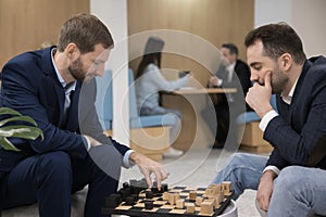 Two office employees, workmates play chess take break during workday