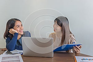 Two office lady sitting with laptop and having happy conversation