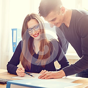 Two office workers discussing about papers at desk