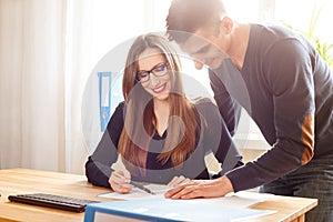 Two office workers discussing about papers at desk