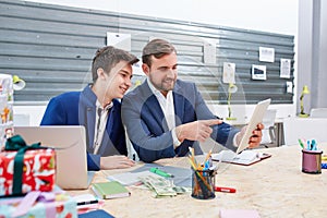 Two office workers look at the tablet where one of them points with a finger.