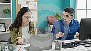 Two office workers, a man and woman, sitting at a table, entangled in a heated argument at their workplace