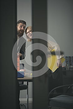 Two office workers in suits look in opening board room door