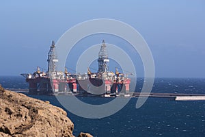 Two oil rigs moored to a dock in an industrial port