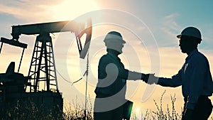 Two oil workers shaking hands in an oilfield