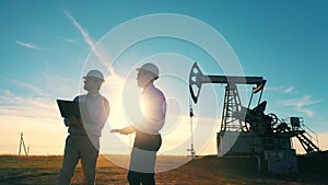 Two oilmen examining an oilfield