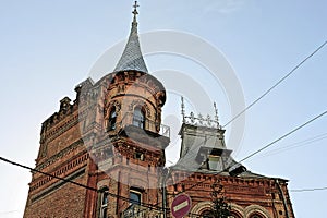 Two old brown brick towers with windows and a balcony