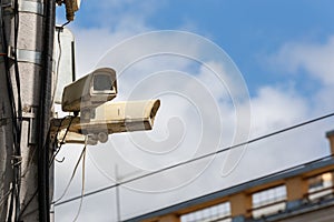 two old cctv security surveillance cameras on street light pole on blue sky background