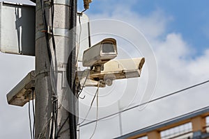 two old cctv security surveillance cameras on street light pole on blue sky background