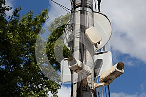 two old cctv security surveillance cameras on street light pole on blue sky background