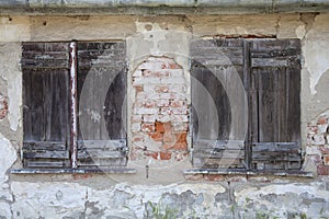 Two old closed windows with wooden shutters in a ruin