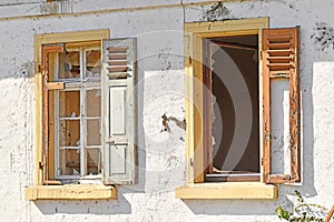 Two old damaged windows with shutters of old abandoned building