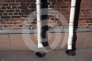 Two old drainpipes on a brick wall