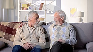 Two old friends talking having fun sitting on sofa, positive mood, conversation