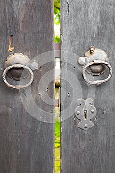 Two old iron ring handles on a door standing ajar