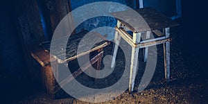 Two old low wooden chair in the dark barn closeup