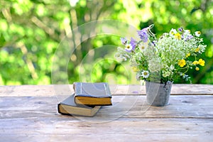 two old paper books in black cover, family bible lie on wooden table in garden, beautiful blurred natural landscape in background