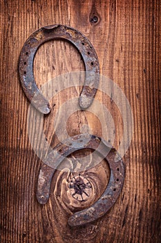 Two old rusted horsehoes on vintage wooden board