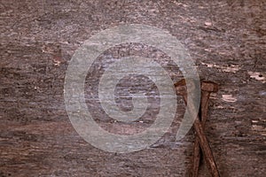 Two old rusty nails rest on a wooden background. Construction concept or religious theme