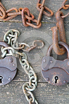 Two old rusty padlock and rusty chain on wooden background. The concept of a couple relationship