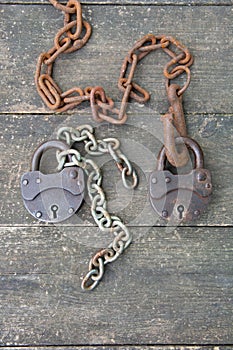 Two old rusty padlock and rusty chain on wooden background. The concept of a couple relationship