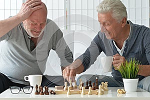 two old senior men playing chess at home