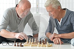 two old senior men playing chess at home