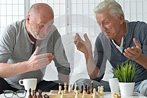 two old senior men playing chess at home