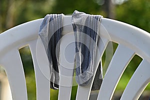 Two old threadbare socks on the back of a white plastic garden chair
