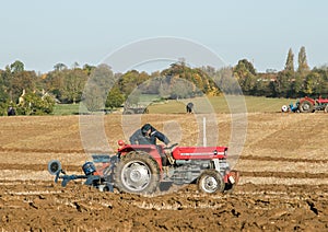 Two old vintage red tractors ploughing