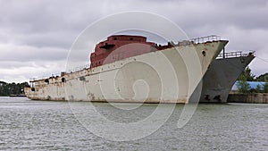 Two old warships are moored on the riverbed against a dramatic sky