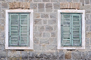 Two old windows with closed shutters on an old house